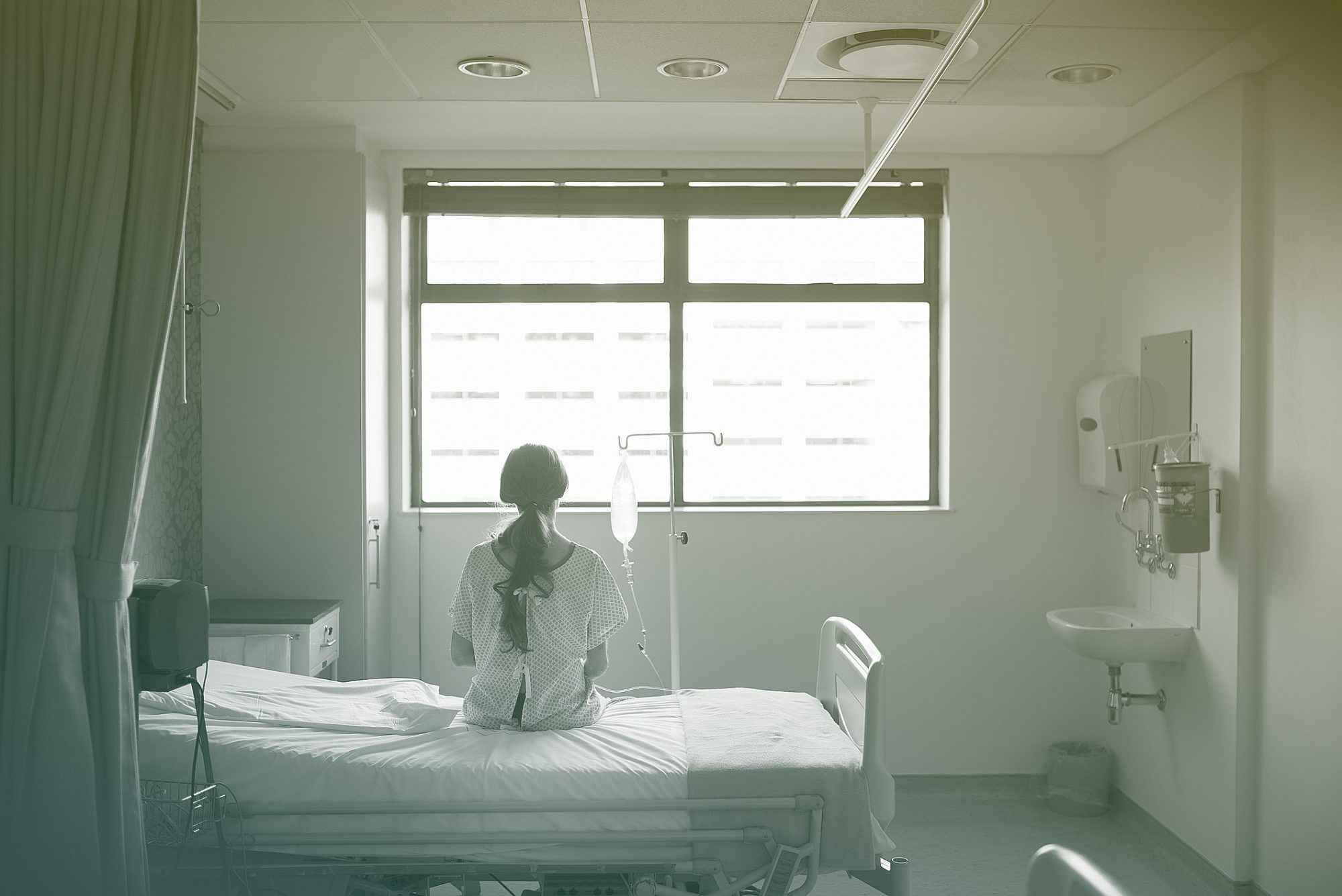 Back view of patient sitting on hospital bed waiting