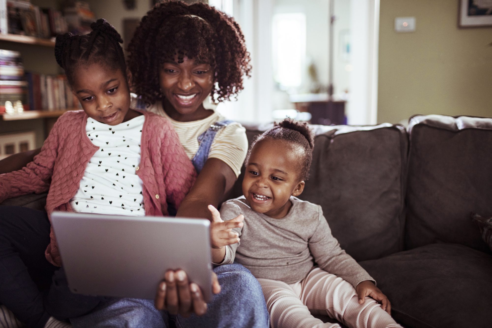 An image of a mom and her kids watching a show on their iPad.