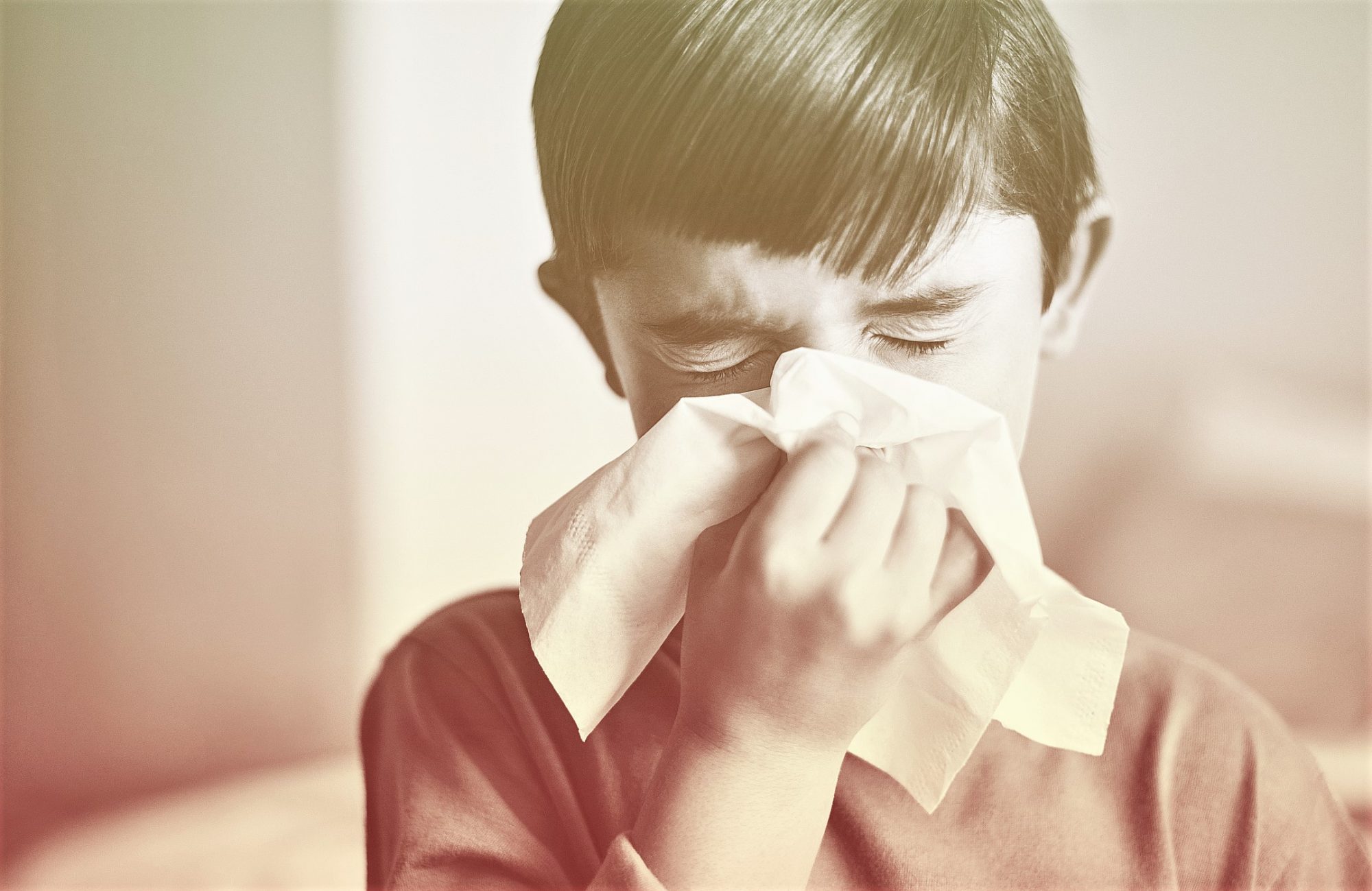 child sneezing into tissue